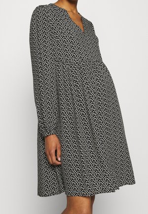 Černé šaty s dlouhými rukávy, výstřihem do V a bílým květinovým vzorem. Rozšířený střih s řaseným pasem, vyrobené z lehké látky.