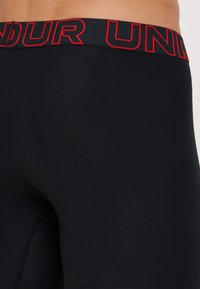 Leggings negre cu o talie elastică lată, având litere roșii îndrăznețe. Material neted, elastic, cu o formă aderentă.