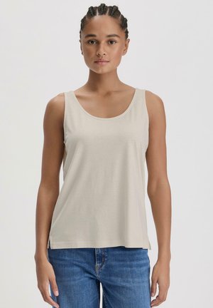 Lichtbeige tanktop van zachte, lichte stof met een ronde halslijn en brede schouderbanden. Gepaard met blauwe jeans.