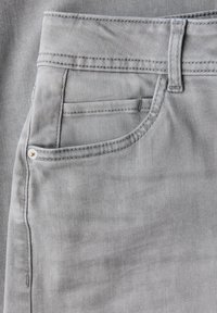 Jeans in denim grigio chiaro con tasca anteriore, taschino per monete, passante per cintura e dettaglio di cucitura visibile.