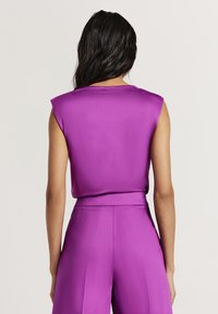 Top aderente senza maniche in raso viola vivace, con una texture liscia e scollatura rotonda, abbinato a pantaloni a vita alta coordinati.
