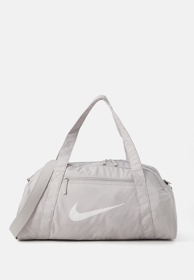 Sivi najlon torba s dvostrukim ručkama, podesivim remenom za rame i bijelim Nike logotipom otisnutim s jedne strane. Ima zatvorene džepove.