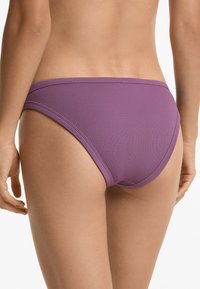 Slip di bikini viola a coste con una vita bassa e elastica, che presenta una superficie testurizzata e bordi lisci.