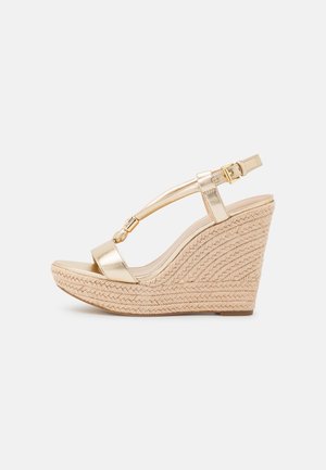 Gylden metallisk kile sandal med flettet jute platform, åben tå, ankelrem og dekorativ perle på T-rem.