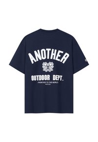 Tmavomodré tričko s bielym textom "ANOTHER OUTDOOR DEPT." a dvoma krížiacimi sa ružami pod ním, plus menší text "FROM DUS TO THE WORLD SINCE 2023."