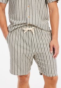 Ensemble en coton rayé composé de lignes verticales noires et crème, avec une taille élastique à cordon de serrage et une chemise décontractée à boutons.