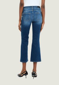 Jeans a palazzo blu scuro in denim, con vita media, due tasche posteriori e un orlo rifinito. Abbinati a tacchi neri.