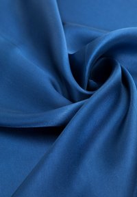 Tissu satin bleu, texture lisse, avec une finition brillante. Le tissu est drapé, mettant en valeur sa douceur et sa fluidité.