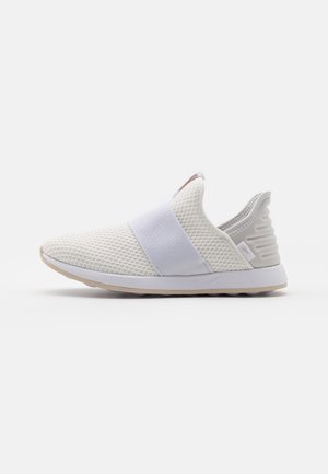 Hvid slip-on sneaker med mesh-overdel, bred elastik over toppen og tekstureret hælkappe med hvid sål og beige ydersål.
