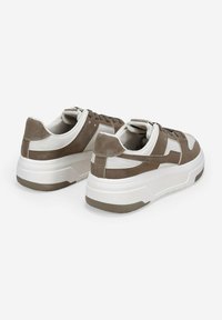 Sneaker marroni e bianchi con tomaia in pelle liscia e suede, suola bianca spessa e dettagli a contrasto sul tallone e sui lati.