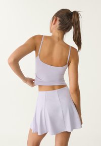 Fialový crop top s tenkými ramienkami v kombinácii s ladiacou plisovanou mini sukňou. Obe kusy sú vyrobené z hladkej, elastickej látky.