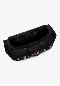 Svart duffelbag med glatt tekstur, med en rød Jumpman-logo og «JORDAN» i hvitt. Glidelåslukking, dobbelthåndtak for enkel bæring.