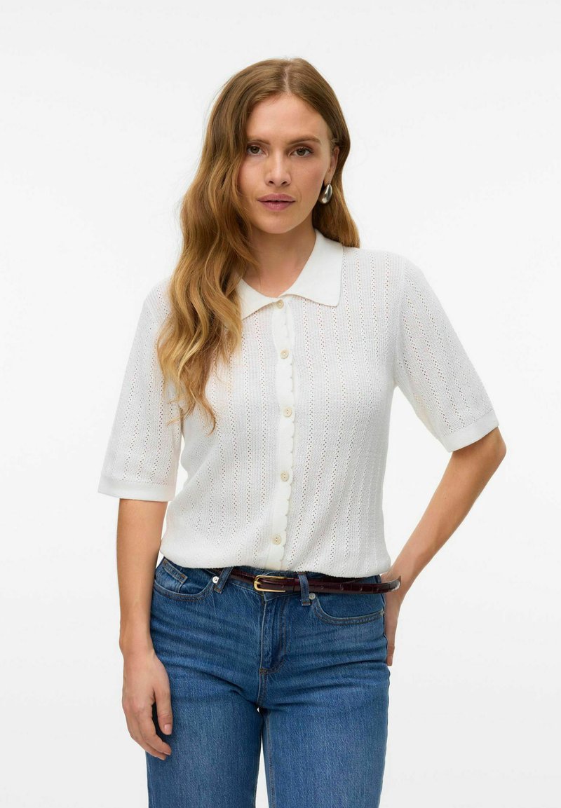 Blusa a maglia bianca a maniche corte con placca di bottoni a scallop e colletto, caratterizzata da un design testurizzato e un tessuto traspirante.