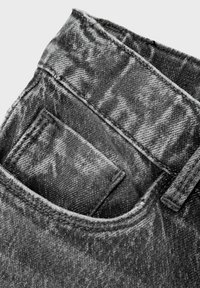 Jeans de mezclilla con cintura alta, bolsillo trasero y color negro desgastado, con costuras visibles y una superficie suave y texturizada.
