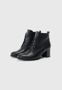 Bottines en cuir noir avec lacets, bout rond et talons carrés sur un fond blanc.