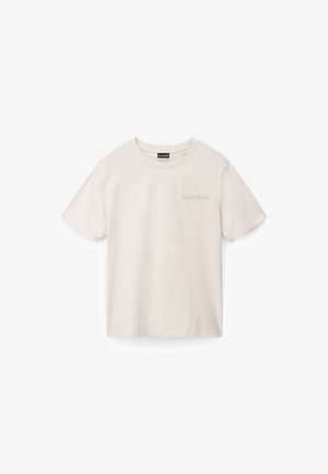 Camiseta de algodón color beige claro con cuello redondo y mangas cortas. Presenta un sutil estampado de logo en el área del pecho izquierdo. Textura suave.