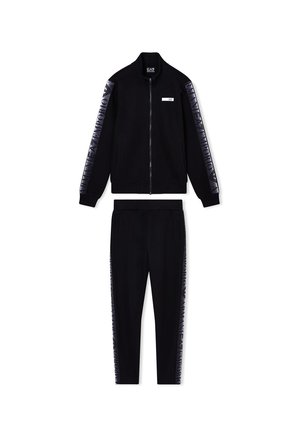 Chándal negro que presenta una chaqueta con cremallera y bordes acanalados, junto con pantalones a juego; ambos tienen rayas laterales brillantes con texto del logotipo.