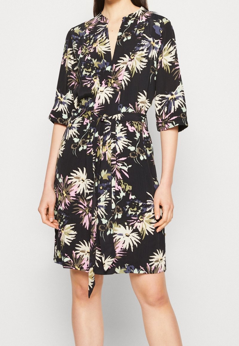 Vestido floral con fondo negro, que presenta patrones vibrantes en amarillo, rosa y verde, mangas cortas y un cinturón de lazo en la cintura.