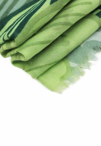 Sciarpa verde realizzata in un tessuto morbido e leggero con un motivo sottile. I bordi sono frastagliati, evidenziando un design a strati in diverse sfumature di verde.