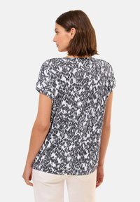 Blusa de manga corta en un patrón abstracto en blanco y negro, con escote redondeado y corte holgado, hecha de tela ligera.