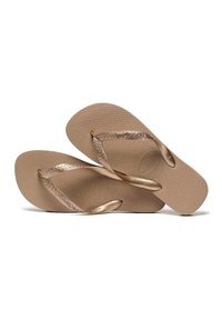 Chinelos de dedo bege com sola texturada, apresentando tiras metálicas douradas com um padrão floral e design minimalista.