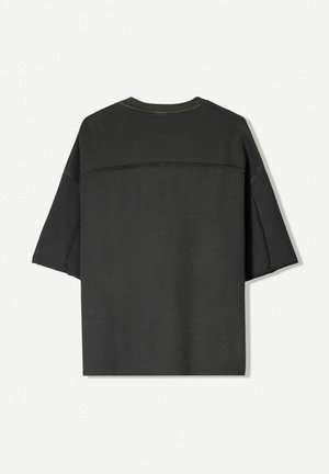 Black short-sleeve oversized t-shirt made of textured fabric, featuring a crew neck and subtle stitching detail across the shoulders.