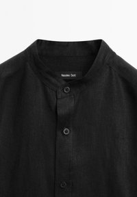 Zwarte linnen blouse met een opstaande kraag, voorzien van twee zwarte knopen aan de voorkant en het "Massimo Dutti" label aan de binnenkant van de halslijn.