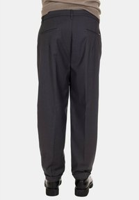 Pantaloni grigi con vestibilità sartoriale, caratterizzati da una parte anteriore liscia, due tasche posteriori e un tessuto liscio e texturizzato. Accompagnati da cuciture sottili.