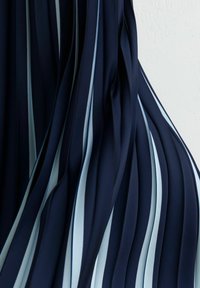 Meresinine voltidega kangas helesiniste triipudega, millel on pehme tekstuur ja voolav disain, rõhutades teravaid kontraste värvi ja mustri vahel.