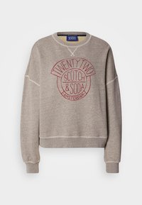 Sudadera gris claro hecha de tela suave, con cuello redondo, hombreras caídas y un estampado de logo circular rojo en el frente.