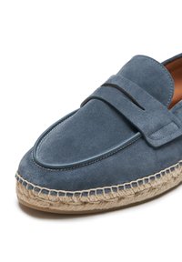 Mocasines de ante azul con un diseño de mocasín de cuero, que presentan una suela de yute cosida y una costura decorativa en la parte superior de la abertura.