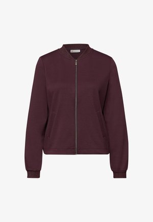 Bordeauxrode jas met ritssluiting, ronde kraag, gestructureerde manchetten en zijzakken. Gemaakt van zachte stof, met een metalen ritsdetail.