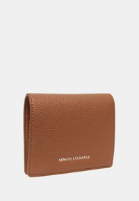 Portafoglio in pelle marrone con texture a granulato, design piegato e logo impresso in basso. Dimensioni compatte, aspetto minimalista.