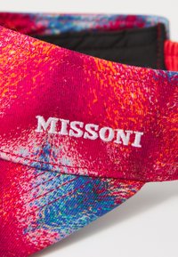 Punane ja sinine mustriga müts, millel on valge tikandiga tekst "MISSOLNI". Valmistatud tekstureeritud kangast ja sirge äärega.