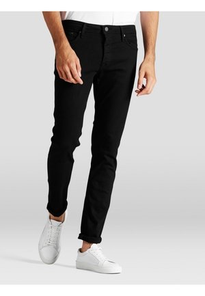Jeans ajustados negros de denim, con un diseño clásico de cinco bolsillos. Combinados con zapatillas blancas para un look casual.
