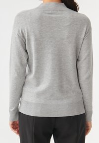 Maglione grigio a maglia con scollo rotondo, polsini e orlo a costine. Texture morbida con una vestibilità rilassata, cuciture visibili lungo le spalle.