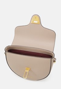 Borsa in pelle beige con una silhouette curva, hardware dorato, chiusura a scatto e fodera interna color bordeaux. Dotata di manico superiore.