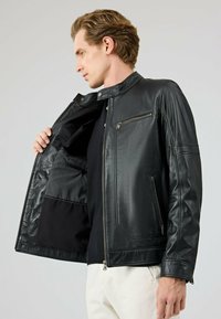 Zwarte leren jas met een ritssluiting aan de voorkant, drukknopen kraag en zijzakken. Gevoerde binnenkant met een gestreept patroon, voorzien van een ritszak en een gladde textuur.