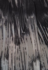 Tejido de patrón en negro y gris con un diseño texturizado y rayado. El material parece ligero, exhibiendo un patrón abstracto y fluido.