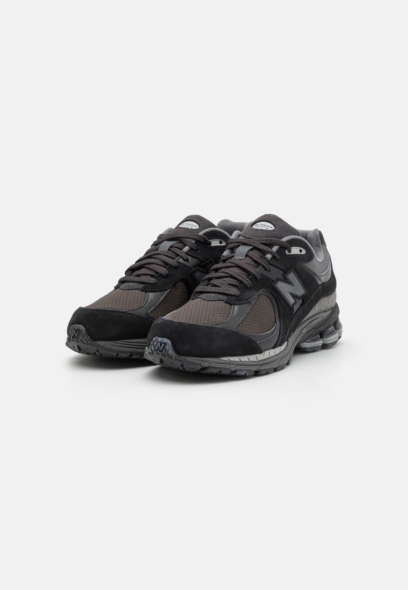 Zwarte sport sneakers van mesh en suede materialen, met een gevoerde zool, gestructureerde accenten en reflecterende merktekens.
