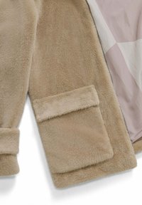 Beige neplederen jas met een gladde structuur, voorzien van een patchzak en een voering in een zachte pastel kleur. Rits sluiting aan één zijde.