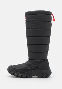 Svart isolerad känga med en quiltad ovandel, rund tå, ribbad sula och ett rött snöre. Texturerade paneler vid vrist och häl.