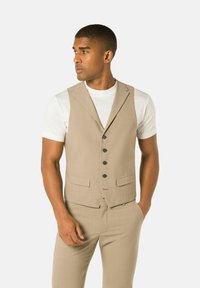 Beige colbert met een notch-lapel, zes knopen en twee voorzakken. Draag het over een wit t-shirt, met een gestructureerde stof.