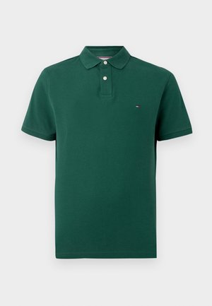 Mörkgrön kortärmad polo skjorta med två vita knappar och en liten rektangulär logotyp på vänster bröst.