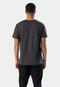 Mørkegrå t-shirt med korte ærmer og rund hals, glat tekstur og lige kant, vist fra bagsiden, båret med sorte bukser.