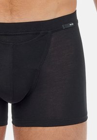 Schwarze Boxershorts aus weichem, dehnbarem Stoff. Mit einer taillierten Passform, elastischem Bund und einer vorderen Tasche mit nahtloser Verarbeitung.