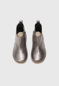 Et par metalliske sølvfargede skinnankleboots med glidelåser på siden og løftestropper bak, vist mot en hvit bakgrunn.