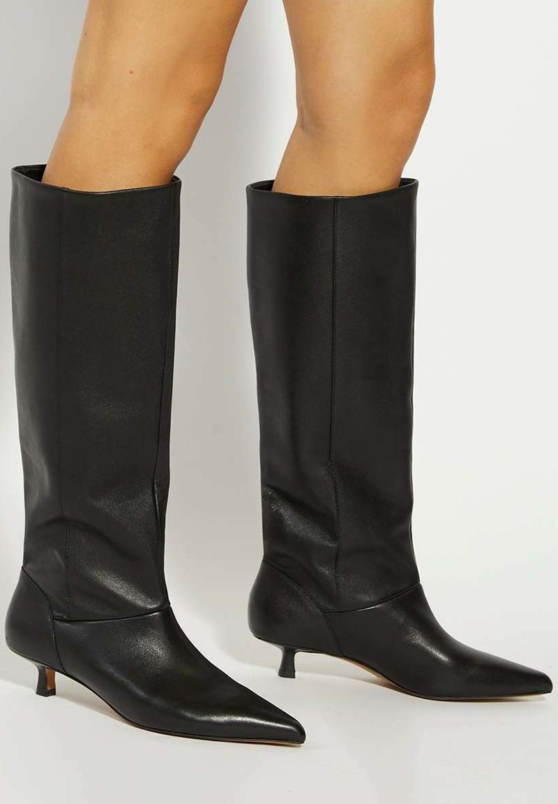 Black leather knee-high boots with a pointed toe, kitten heel, and smooth texture. Fitted design with a sleek appearance.