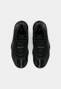 Fekete sportcipők fényes patent bőrből és hálós anyagból, kék és arany díszítéssel, kerek orral és lapos fűzőkkel.