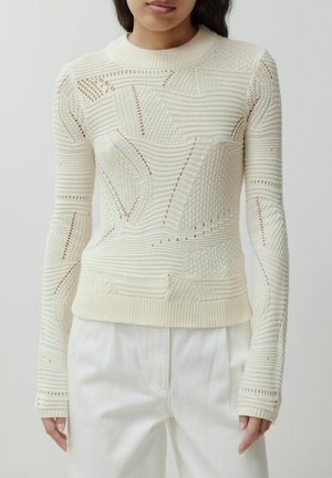 Gebreide trui in gebroken wit, met textuurpatronen, openwerkdetails en een geribbelde ronde hals. Lange mouwen met aangesloten manchetten.